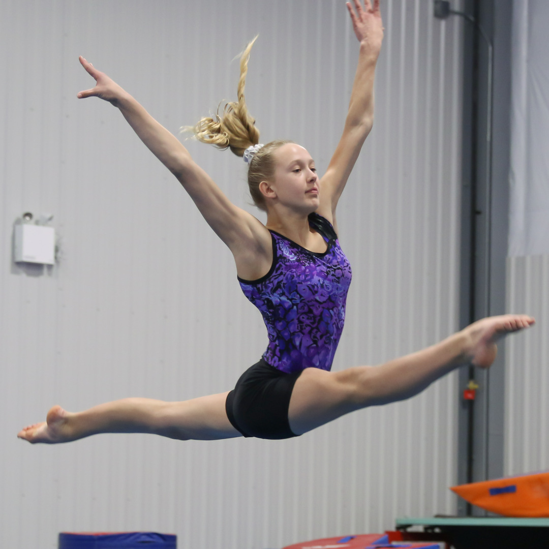 Gymnast performing a split leap at Gymworld gymnastics facility in Northwest London.
