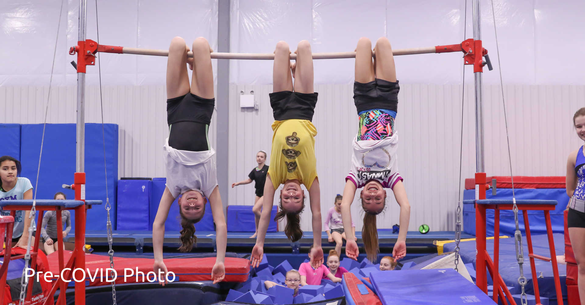 Gymnastics PD Camps at Gymworld - Smiling girls hanging upside down on the bars at the Gymworld in London.