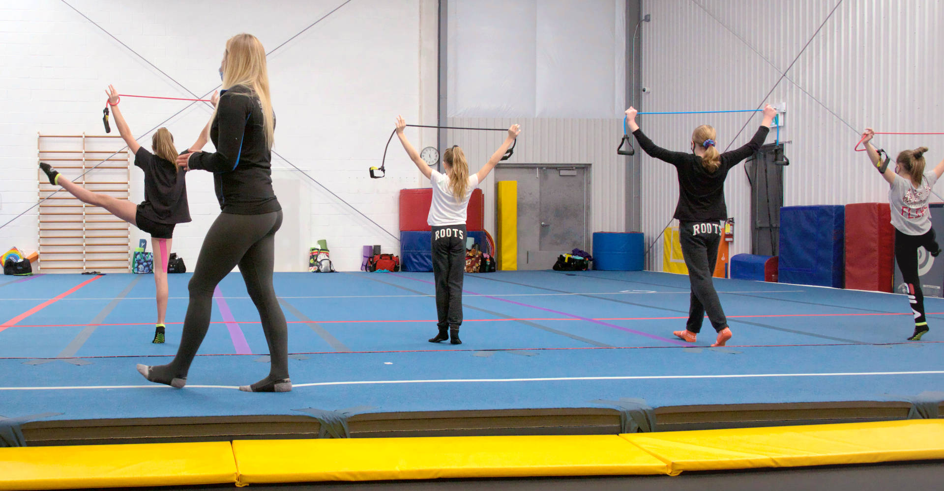 Girls warming up on the spring floor with their gymnastics coach at Gymworld Adventures in Gymnastics facility in Northwest London