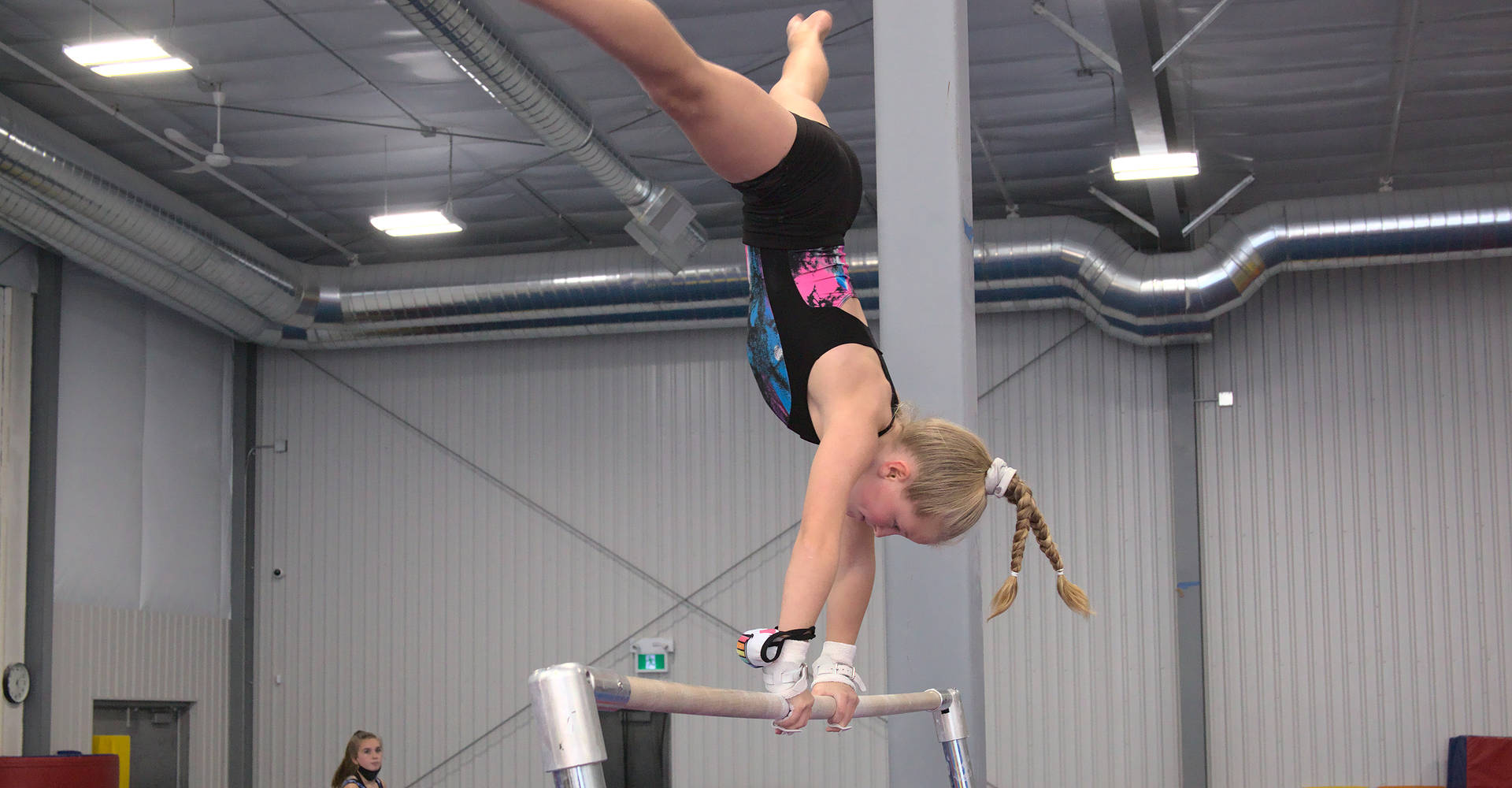 A young gymnast practicing a cast to straddle handstand on the bars at the Gymworld Adventures in Gymnastics facility in London Ontario