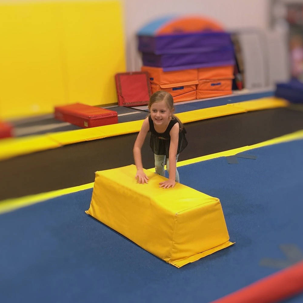 Gymnast performing a split leap at Gymworld gymnastics facility in Northwest London.