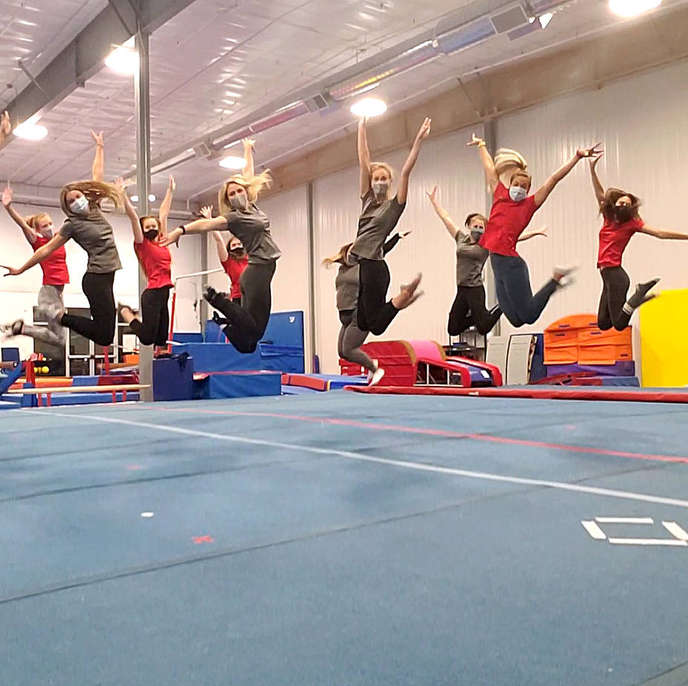 Gymworld gymnastics coaches do a group jump.