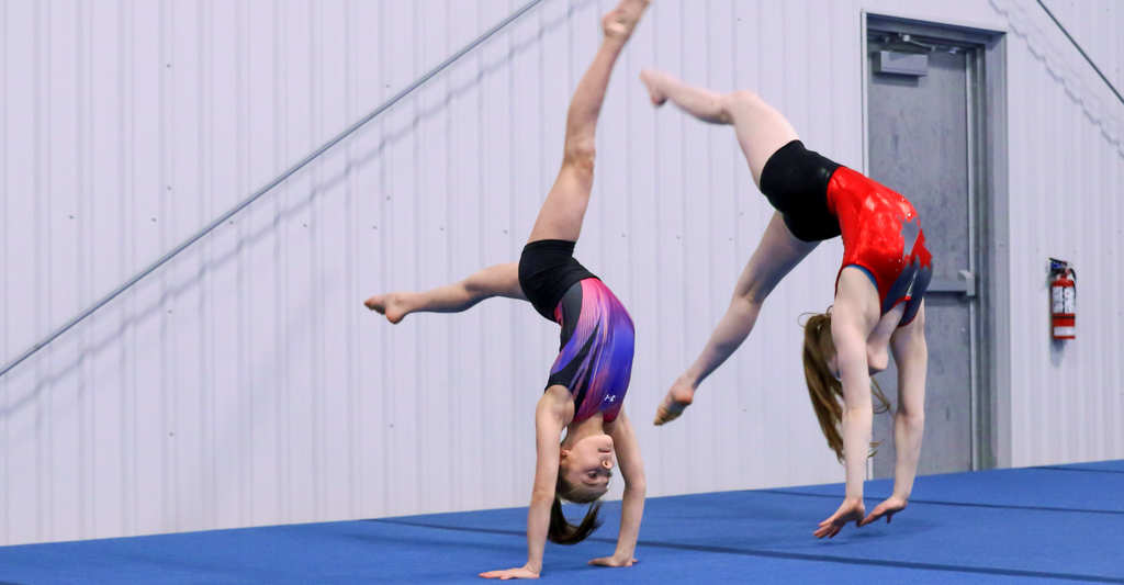 Tumbling Gymnastics Classes at Gymworld - Gymnast performing a back walkover on a balance beam at Gymworld gymnastics facility in Northwest London